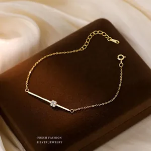 Detail view of an elegant gold-tone bar bracelet with crystal accent on a luxury display