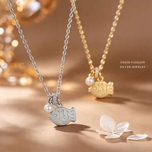 Macro view of silver fish pendant necklace with pearl on elegant warm background