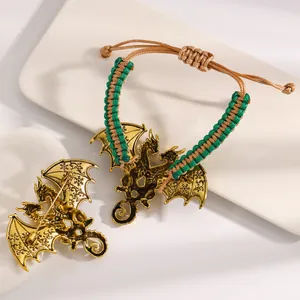 Detail view of vintage golden dragon charm on a green braided bracelet and brooch.