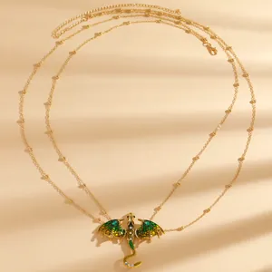 Detailed view of an intricate green enamel dragon pendant on a delicate gold beaded chain.