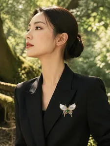Exquisite butterfly brooch with natural shell wings and green stone on a black blazer.