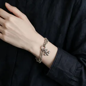 Detailed view of vintage silver chain bracelet with fleur-de-lis charm on hand