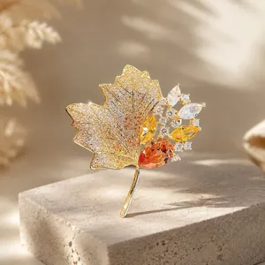 Detaillierte Nahaufnahme einer luxuriösen Ahornblatt-Brosche mit leuchtend orangen Kristallen.
