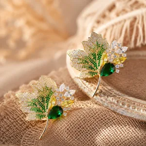 Detailansicht einer eleganten Ahornblatt-Brosche mit leuchtend grünen Strasssteinen