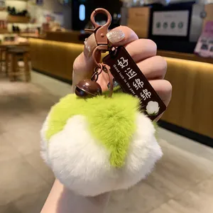 Detailansicht eines lindgrünen und weißen Plüsch-Pompon-Schlüsselanhängers in der Hand gehalten.