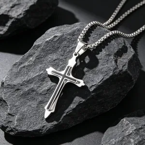 Sleek stainless steel cross pendant necklace with black inlay design for men shown on rocks