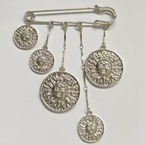Detailansicht einer silbernen Sicherheitsnadel-Brosche mit fünf Sonnenanhängern