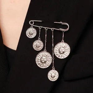 Broche épingle de sûreté argentée style punk avec breloques soleil sur blazer noir.