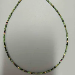 Vue détaillée d'un collier en perles de rubis zoïsite avec des touches dorées.