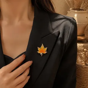 Detailed view of an elegant gradient maple leaf brooch pinned to a black blazer lapel.