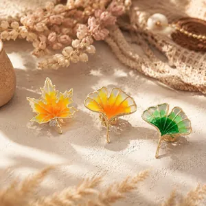 Close-up of retro maple and ginkgo leaf enamel pins with gold trim