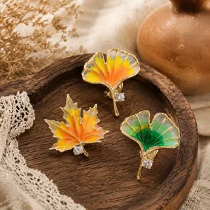 Detailed view of vintage enamel ginkgo and maple leaf brooches with crystal accents