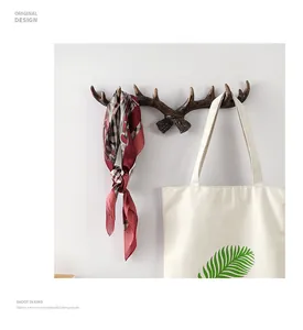 Vintage antler decorative wall hook shown holding a silk scarf and a canvas tote bag