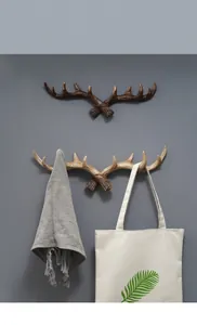 Vintage gewei wandhaken van hars gemonteerd op muur met tas en sjaal hangend