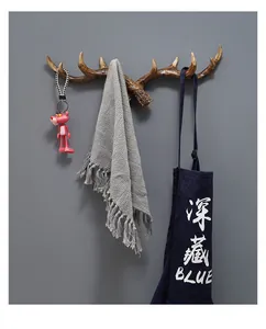 Vintage deer antler wall hook shown holding a towel, apron, and a pink keychain