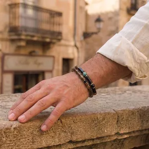 Close-up of men's handmade beaded bracelets with semi-precious stones in sunlight