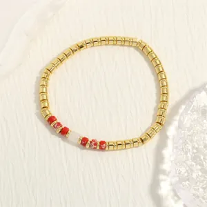 Gedetailleerde weergave van handgemaakte kralenarmband met gouden en rode kralen.
