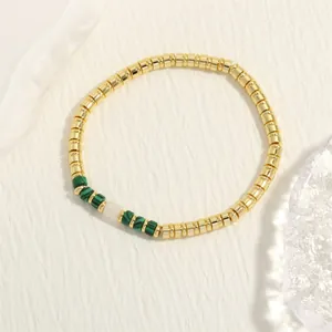 Detailopname van een handgemaakte bohemian kralenarmband met gouden en malachietgroene kralen