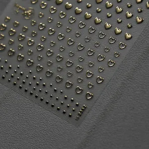 Vintage gold heart nail art stickers with 3D bronzing effect on a textured background