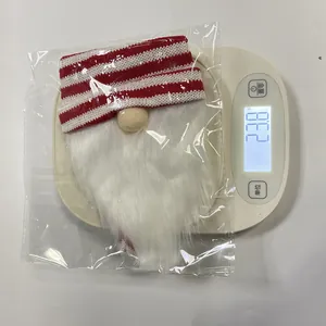 Detailed view of a Christmas gnome bottle cover with striped knit hat on a scale, 23 grams