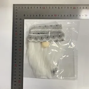 Knitted Christmas gnome wine bottle cover with white beard shown being measured by a ruler