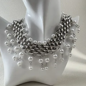 Detail view of a chunky silver-toned chain necklace with elegant dangling white pearls
