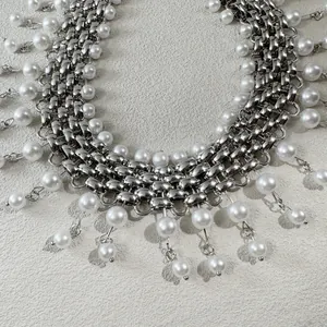 Close-up detail of a silver punk chain necklace featuring elegant pearl fringe accents