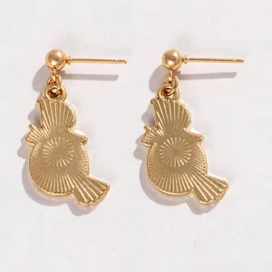 Détail macro de boucles d'oreilles dorées en forme d'oiseau avec une texture rayons de soleil.
