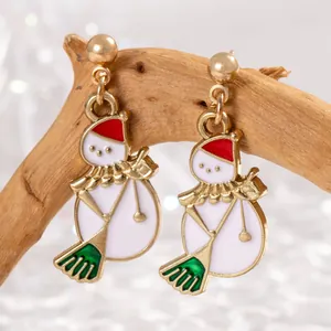 Détail de boucles d'oreilles bonhomme de neige de Noël avec bonnet rouge et balai.