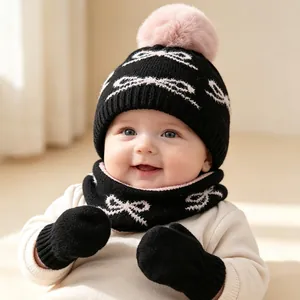 Gros plan d'un ensemble d'hiver pour bébé avec bonnet noir, pompon rose et motifs nœuds