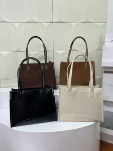 Quatre sacs fourre-tout minimalistes en cuir mat et poli sur une plateforme blanche