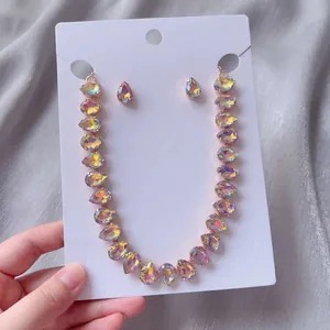Détail de la parure de bijoux collier et boucles d'oreilles en cristal larme irisé.