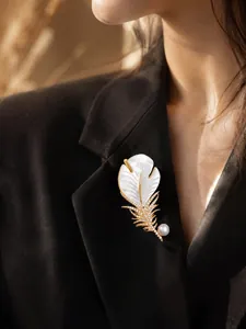 Detail view of elegant feather brooch with mother-of-pearl and crystals on black blazer
