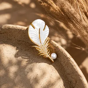 Close-up of white mother-of-pearl feather brooch with shimmering diamonds and a pearl
