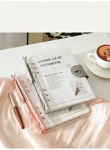 Two transparent 6-ring PVC binders stacked on a desk with a coffee cup