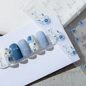 Detailed macro view of blue embossed floral nail art stickers on matte manicured nails