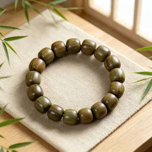Detailansicht eines Armbands aus grünem Sandelholz auf einer Leinenmatte mit Bambusblättern