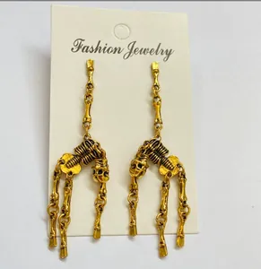 Close-up of vintage gold skeleton earrings featuring detailed bone joints and skull charms.