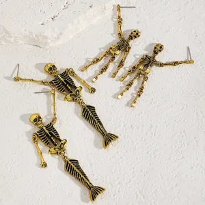 Detailed view of gothic gold-tone skeleton and mermaid skeleton drop earrings