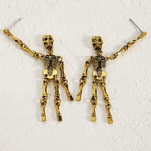 Close-up of gothic vintage gold articulated skeleton earrings on textured white background
