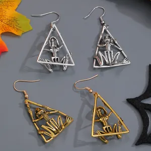 Detailed macro view of Gothic skeleton triangle earrings in silver and gold finishes.