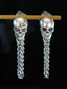 Detailed close-up of gothic silver skull earrings with long chunky chain tassels on black bg
