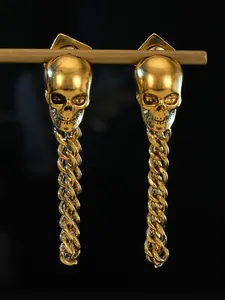 Detailed macro view of gothic gold skull drop earrings featuring long heavy punk style chains