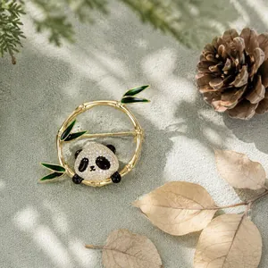 Close-up of an elegant panda and bamboo brooch with crystals and green enamel detail.