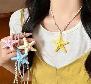 Dettaglio di una collana di perline colorate con un grande ciondolo a stella marina