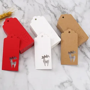 Dettaglio di etichette regalo natalizie con ritaglio di renna in rosso, bianco e kraft