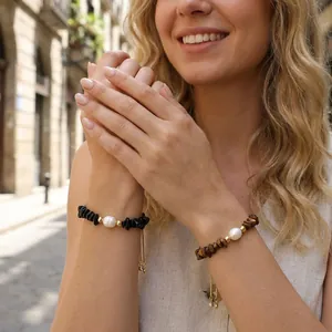 Close-up detail of irregular gemstone bracelets with freshwater pearls on model's wrist