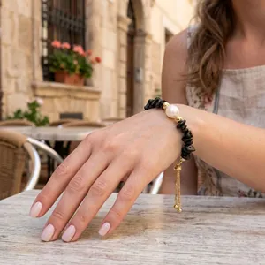 Handmade bracelet with black irregular stones and a white freshwater pearl on a model.