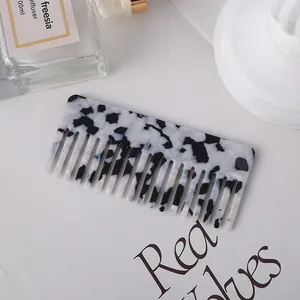 Close-up detail of a black and white marble pattern acetate wide-tooth hair comb