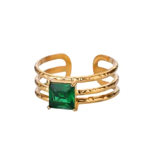 Macro view of gold three-layer open ring featuring a square emerald green gemstone